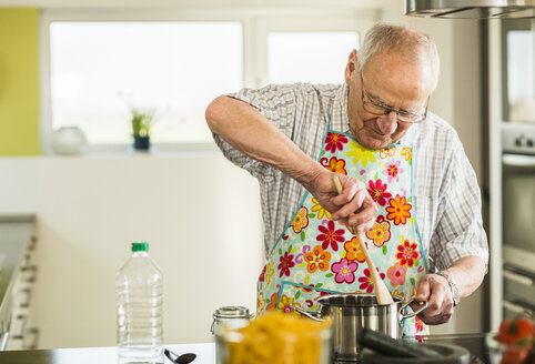 Älterer Mann beim Kochen in der Küche - UUF003500