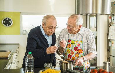 Zwei ältere Freunde kochen in der Küche - UUF003502