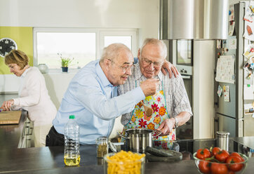 Senior friends cooking in kitchen - UUF003506