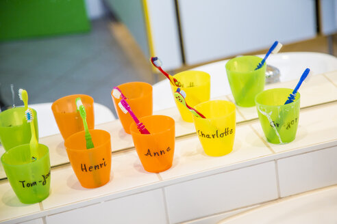 Plastikbecher mit Zahnbürsten mit Mähnen von Kindern im Kinderzimmer - JFEF000603