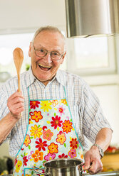 Glücklicher älterer Mann beim Kochen in der Küche - UUF003511