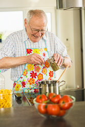 Älterer Mann beim Kochen in der Küche - UUF003512