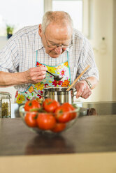 Älterer Mann beim Kochen in der Küche - UUF003513