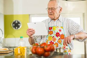 Älterer Mann mit digitalem Tablet beim Kochen in der Küche - UUF003514