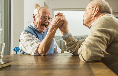 Two senior friends arm wrestling stock photo