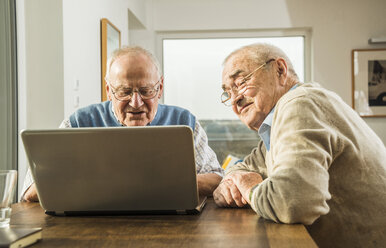 Zwei ältere Freunde schauen auf einen Laptop - UUF003548