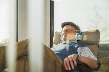 Älterer Mann zu Hause beim Entspannen mit Kopfhörern - UUF003551