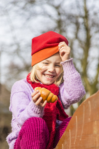 Deutschland, Kiel, Kleines Mädchen mit roter Mütze hält Croissant, lizenzfreies Stockfoto