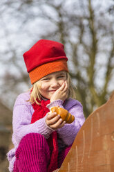 Germany, Kiel, Little girl with red cap holding croissant - JFEF000588