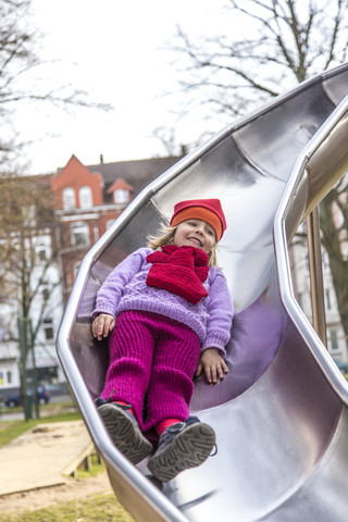 Deutschland, Kiel, Kleines Mädchen mit roter Mütze spielt auf Schießstand, lizenzfreies Stockfoto
