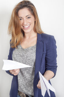 Porträt einer lächelnden Frau mit Papierfliegern - PATF000027