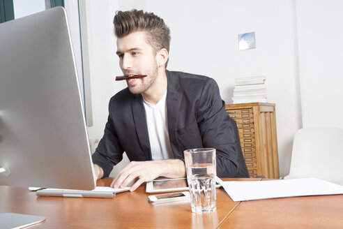 Junger Mann arbeitet am Schreibtisch in einem Büro - PATF000041