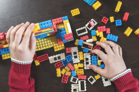 Kinderhände spielen mit Bauklötzen auf einem Tisch, lizenzfreies Stockfoto