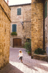 Italien, Toskana, Pienza, Kleines Mädchen läuft durch Gasse in historischer Altstadt - GSF000953