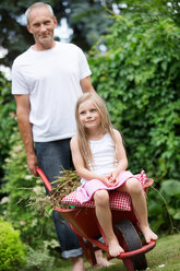 Mann schiebt seine kleine Tochter in einer Schubkarre sitzend - WESTF021165