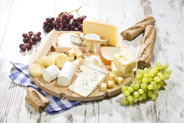 Käseteller mit verschiedenen Käsesorten, Baguette und Weintrauben auf Holz - MAEF009869