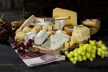 Cheese platter with different sorts of cheese, baguette and grapes on wood - MAEF009872