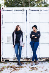 Two female friends standing in front of a container - DAWF000295