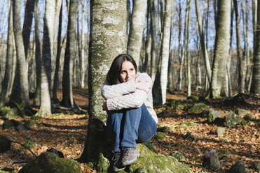 Woman sitting on a rock in a beech forest - GEMF000071