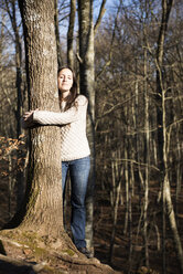 Frau umarmt eine Buche im Wald - GEMF000073