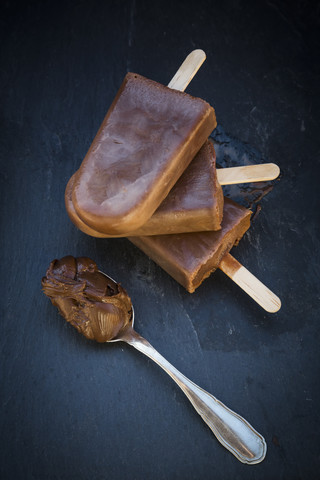 Nutella-Eis am Stiel, Löffel mit Nutella auf Schiefer, lizenzfreies Stockfoto