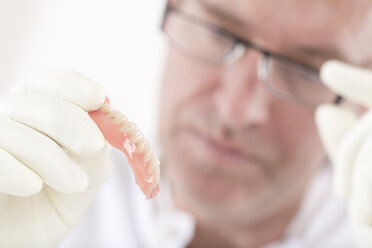 Dental technician examining dentures - DRF001513