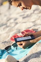 Griechenland, junge Frau liest E-Book am Strand - BZF000051