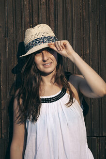 Portrait of woman with summer hat in front of wooden wall - BZF000053