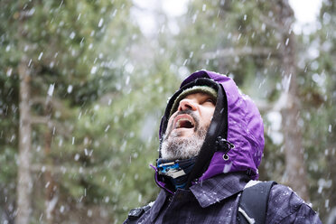 Bärtiger Mann, der bei Schneefall in den Wald schaut - GEMF000080