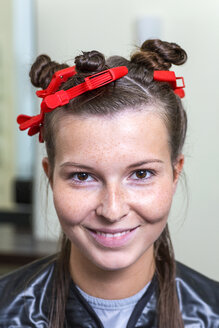 Porträt einer lächelnden jungen Frau mit Lockenwicklern im Haar - DRF001524