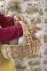 Girl's hands holding wickerbasket with Easter eggs - FSF000332