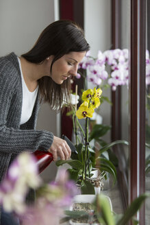 Frau mit Sprühflasche kümmert sich um Orchidee - SHKF000268