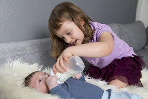 Kleines Mädchen füttert neugeborenen Bruder mit Babyflasche - ROMF000058