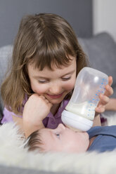 Kleines Mädchen füttert neugeborenen Bruder mit Babyflasche - ROMF000060