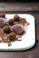 Schokoladentrüffel und Kakaopulver auf Holzbrett - MYF000905