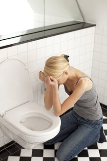 Verzweifelte magersüchtige junge Frau auf der Toilette - DRF001499
