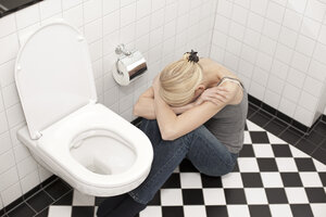 Verzweifelte magersüchtige junge Frau auf der Toilette - DRF001535