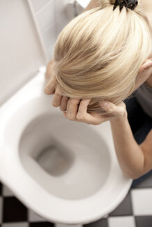 Verzweifelte magersüchtige junge Frau auf der Toilette - DRF001538
