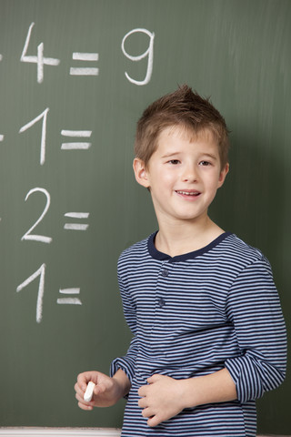 Schuljunge an der Tafel mit arithmetischen Aufgaben, lizenzfreies Stockfoto