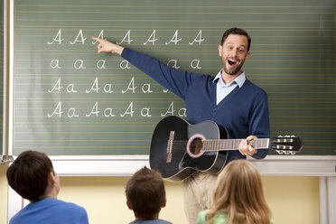 Lehrer mit Gitarre an der Tafel zeigt Variationen des Buchstabens A - MFRF000110