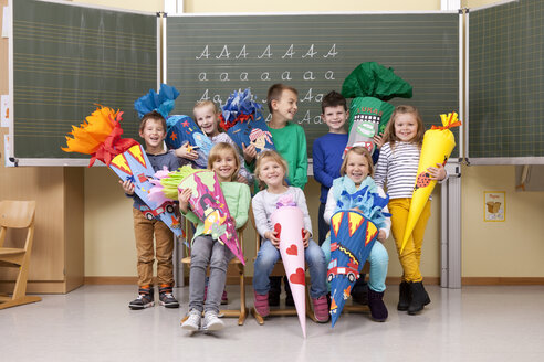 Gruppe glücklicher Schüler mit Schultüten im Klassenzimmer - MFRF000154