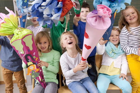 Gruppe glücklicher Schüler mit Schultüten im Klassenzimmer, lizenzfreies Stockfoto