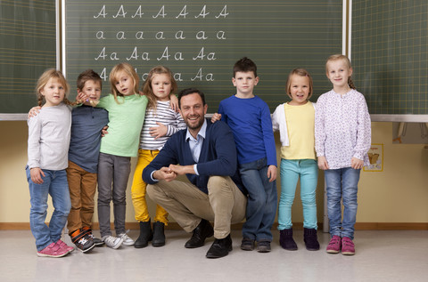 Glückliche Lehrerin mit Schülern im Klassenzimmer, lizenzfreies Stockfoto