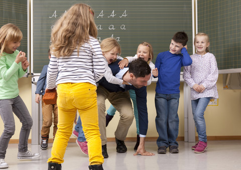 Teacher with playful pupils in classroom stock photo