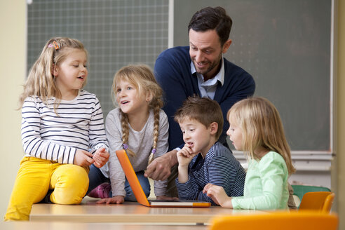 Lehrerin mit Schülern, die einen Laptop im Klassenzimmer benutzen - MFRF000121