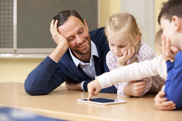 Lehrerin mit Schülern, die ein digitales Tablet im Klassenzimmer benutzen - MFRF000100