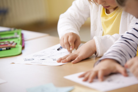 Schulmädchen arbeiten an Arbeitsblättern im Klassenzimmer, lizenzfreies Stockfoto