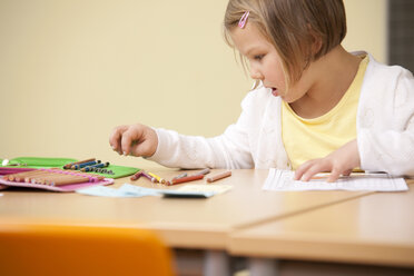 Schoolgirl at school desk with color pencils - MFRF000127