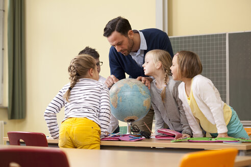 Teacher and pupils looking at globe in classroom - MFRF000129