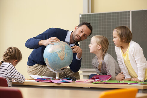 Lehrer und Schüler betrachten den Globus im Klassenzimmer - MFRF000130